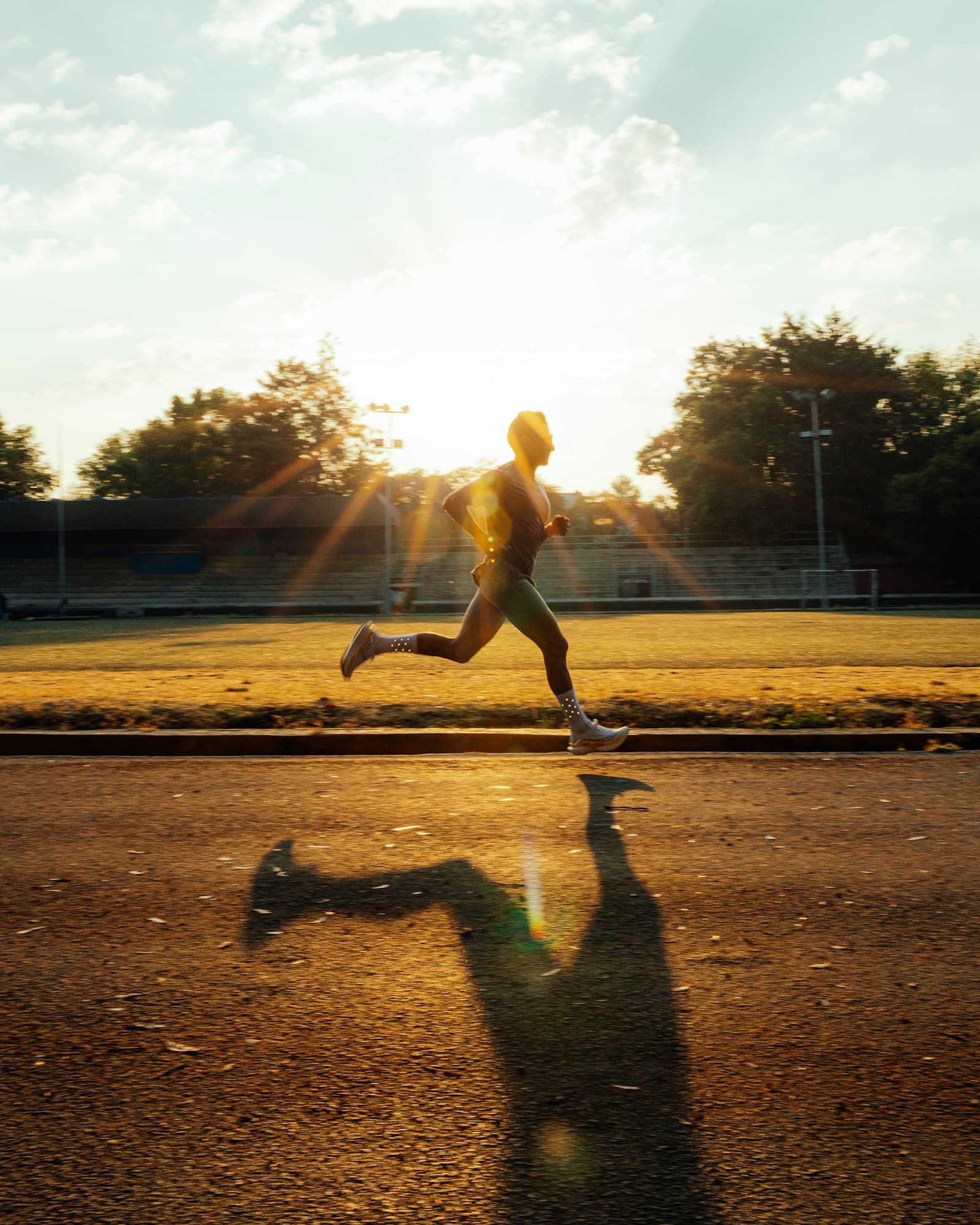 A runner sprinting on a track at golden hour